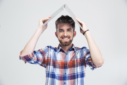 Mann hält einen Laptop schützend als Dach über seine Kopf